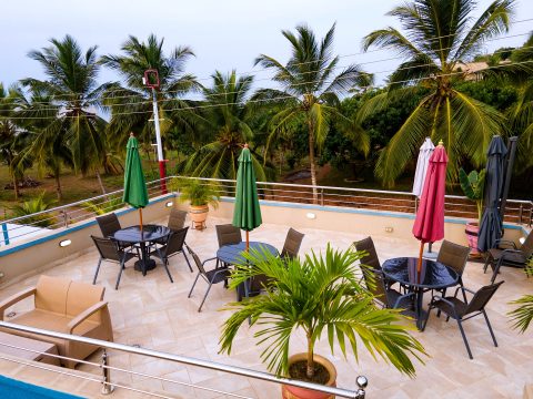 Rooftop terrace with dining tables, parasols and potted palms