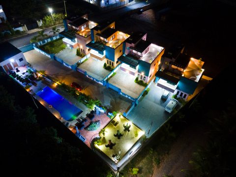 Aerial night view of the lit pool, terraces and apartments