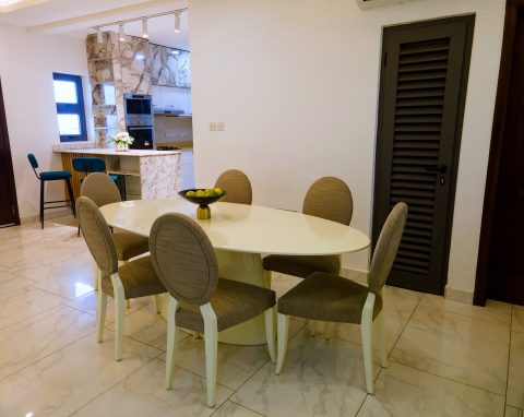 Brown apartment dining table for six, with the kitchen bar behind