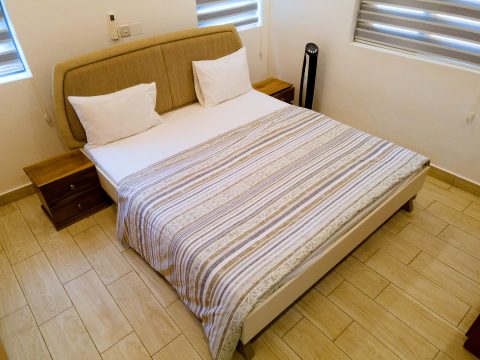 Brown apartment bedroom with an upholstered double bed and bedside table