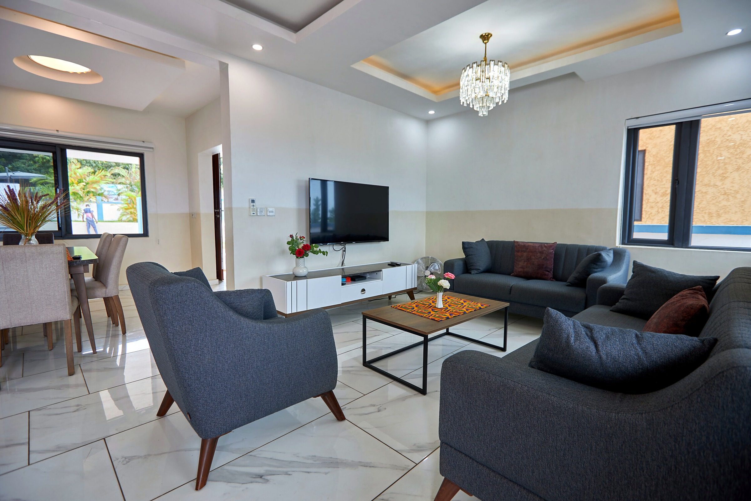 Pink apartment living room with grey sofas, chandelier and TV