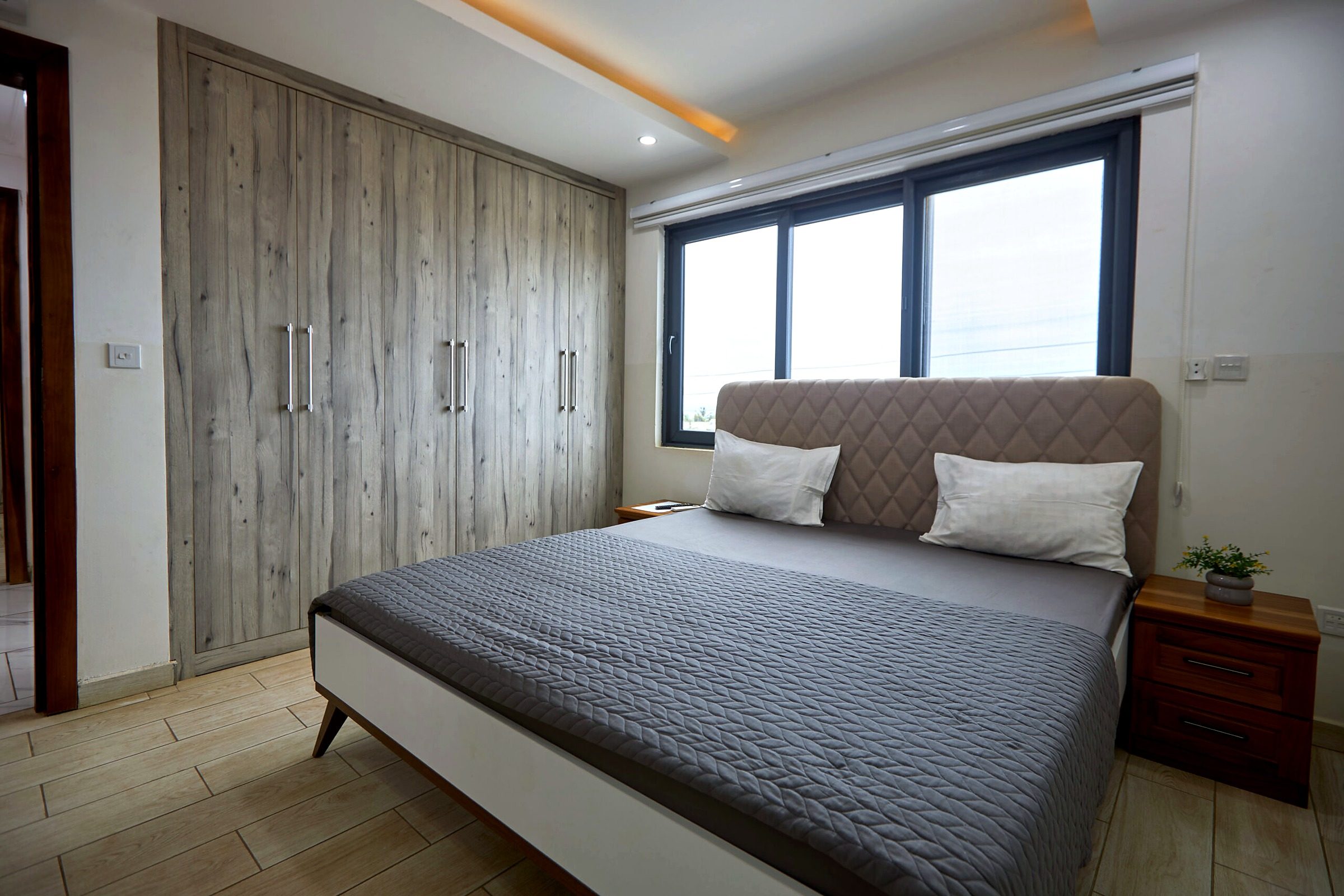 Pink apartment bedroom with an upholstered bed and full-height wardrobe