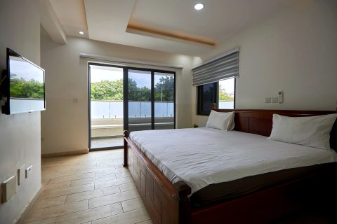 Orange apartment bedroom with a double bed, wall-mounted TV and sliding doors to a balcony